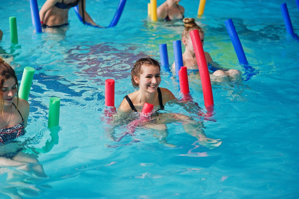 Aquagym class with fasting girl in the water holding a chip