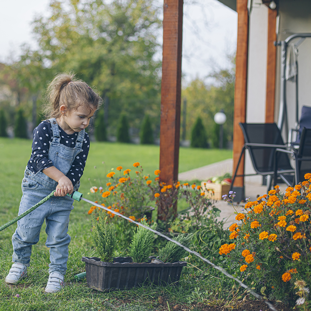 enfant arrose le jardin avec recuperateur d'eau